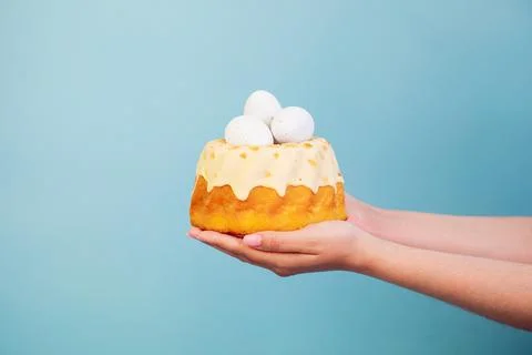 Easter cake with eggs in hands on blue background. Polish babka - traditional Stock Photos