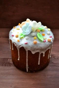 Easter cake with glace icing and colorful decoration. Vertical photo, wooden Stock Photos