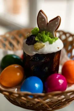 Easter cake with a lit candle. Easter colorful eggs in a basket on the table Stock Photos