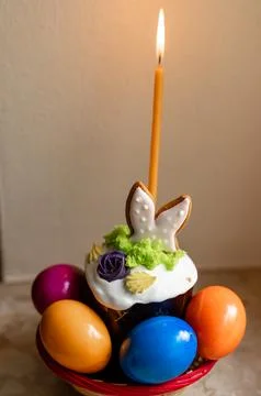 Easter cake with a lit candle. Easter colorful eggs in a basket on the table Foto stock