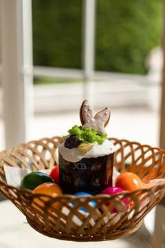 Easter cake with a lit candle. Easter colorful eggs in a basket on the table Stock Photos