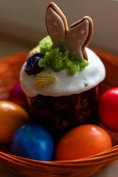 Easter cake with a lit candle. Easter colorful eggs in a basket on the table Stock Photos