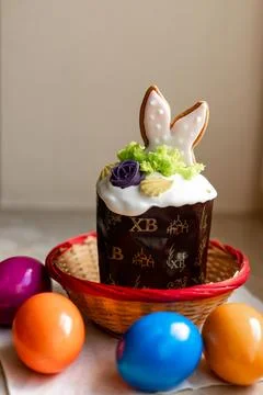 Easter cake with a lit candle. Easter colorful eggs in a basket on the table Stock Photos