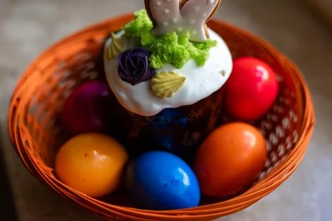 Easter cake with a lit candle. Easter colorful eggs in a basket on the table Stock Photos