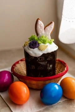 Easter cake with a lit candle. Easter colorful eggs in a basket on the table Stock Photos