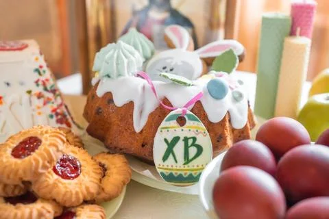 Easter cake with painted eggs, apples and cookies on table in home kitchen Stock Photos