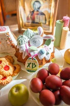 Easter cake with painted eggs, apples and cookies on table in home kitchen Stock Photos