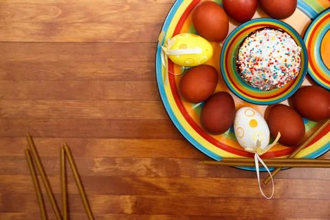 Easter cake with painted eggs on a table made of natural wood, next wax candles. Stock Photos