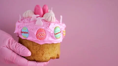 Easter cake with pink icing and colorful decorations  on a pink background. Stock Footage 296829113