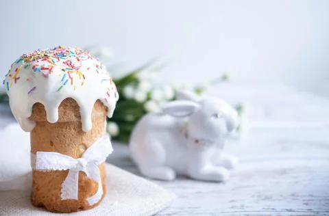 Easter cake, with a porcelain rabbit in the background, on a white table. Sel Stock Photos