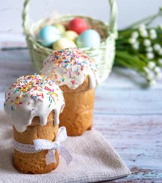 Easter cake with spring flowers and colorful eggs in a basket on a white tabl Stock Photos
