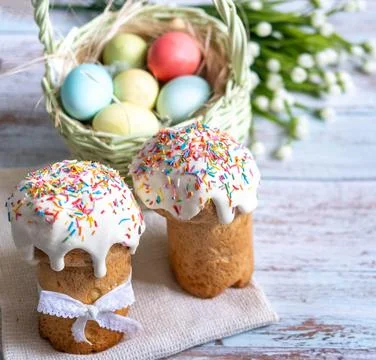 Easter cake with spring flowers and colorful eggs in a basket on a white tabl Stock Photos