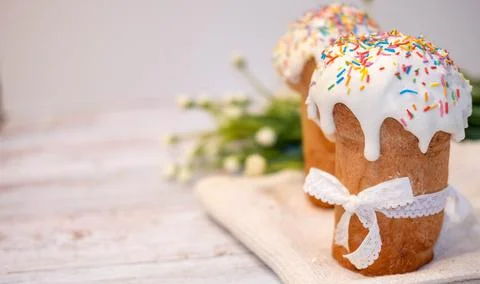 Easter cake with spring flowers and colorful eggs in a basket on a white tabl Stock Photos