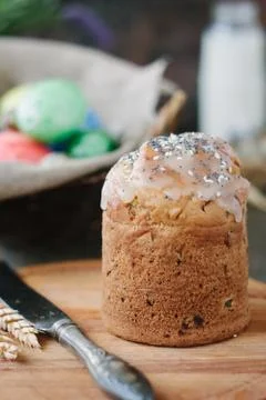 Easter cake standing on board against the basket with easter eggs. Stock Photos