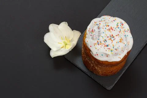 Easter cake on a stone board and tulip flower with black background. Stock Photos
