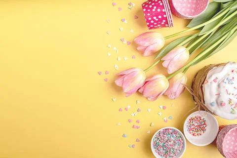 Easter cake with tulips, eggs and baking items top view on yellow background  Stock Photos