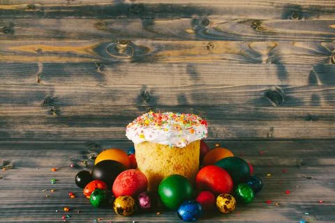 Easter cake on a wooden background. Multi-colored Easter eggs. Stock Photos