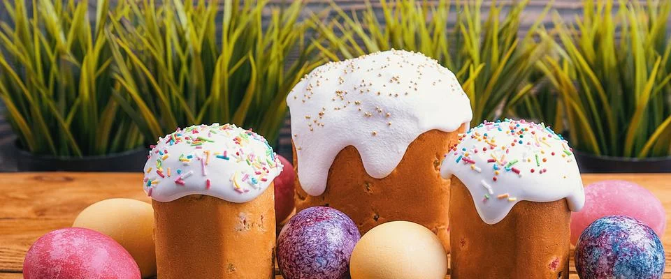 Easter cakes and Easter colored eggs on a wooden background. Stock Photos