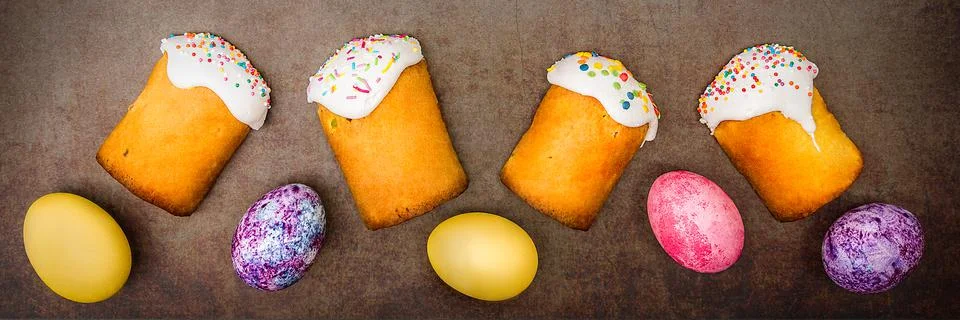 Easter cakes and Easter colored eggs on a dark background. Stock Photos