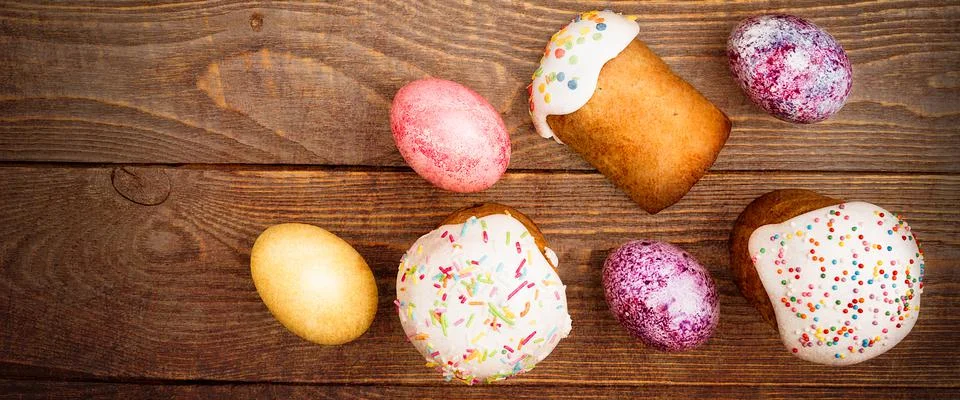 Easter cakes and Easter colored eggs on a wooden background. Stock Photos