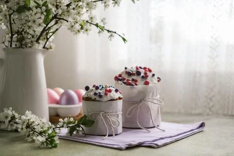 Easter cakes, multi-colored painted eggs and vase of blossoming cherry branch Stock Photos