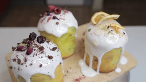Easter cakes with white icing, decorated with various berries and an orange Stock Footage 128567017