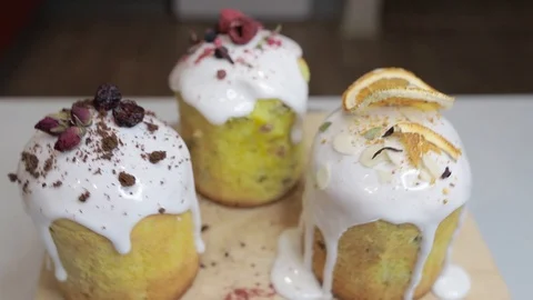 Easter cakes with white icing, decorated with various berries and an orange Stock Footage 128567036