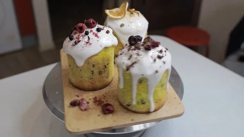 Easter cakes with white icing, decorated with various berries and an orange Stock Footage 128567048