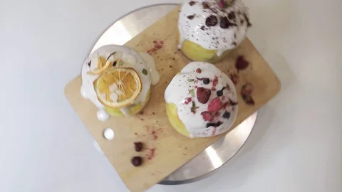 Easter cakes with white icing, decorated with various berries and an orange Stock Footage 128567058