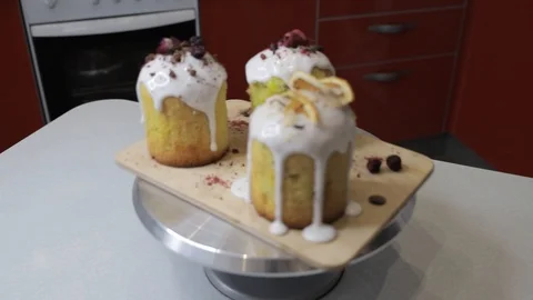 Easter cakes with white icing, decorated with various berries and an orange Stock Footage 128567072