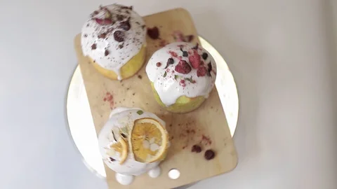 Easter cakes with white icing, decorated with various berries and an orange Stock Footage 128567074