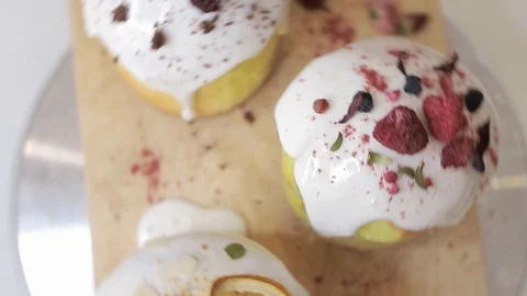 Easter cakes with white icing, decorated with various berries and an orange Stock Footage 128567093