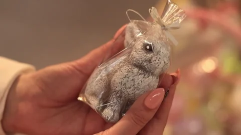 Easter candle in the shape of a bunny. Women's hands hold a hare candle close-up Stock Footage 270155371