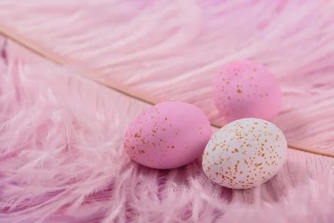 Easter candy chocolate eggs and almond sweets with pink feathers Foto stock