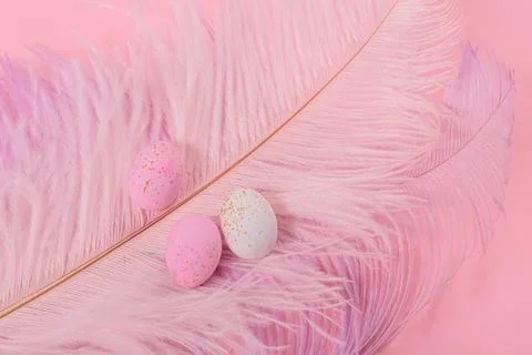 Easter candy chocolate eggs and almond sweets with pink feathers Stock Photos