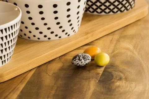 Easter candy eggs on wooden surface besides withe bowls with black pattern Stock-Fotos