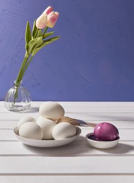 Easter card. Eggs, brush, paint, a bouquet of tulips on a white table on a li Stock Photos