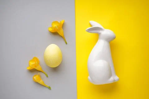 Easter ceramic bunny with yellow easter egg and..freesia flower on a yellow-g Foto stock