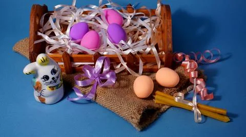 Easter with chicken eggs of different colors with a rabbit figurine on a linen b Stock Photos