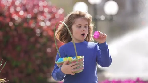 Easter child in blossom spring park. Kid hunting Easter eggs near tulips. Kid Stock Footage 317371868