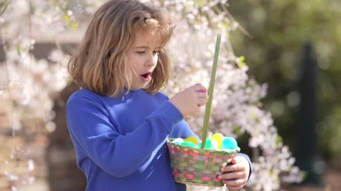 Easter child in blossom spring park. Kid hunting Easter eggs near tulips. Kid Stock Footage 318693994