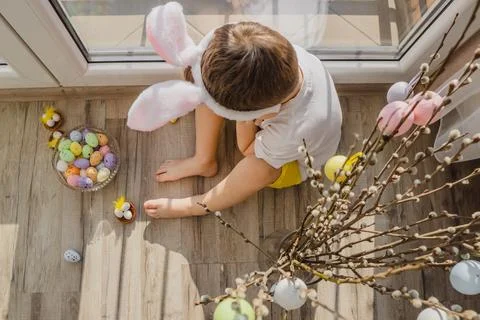 Easter. Child with color eggs for easter. Boy in bunny ears sit on the floor Stock Photos
