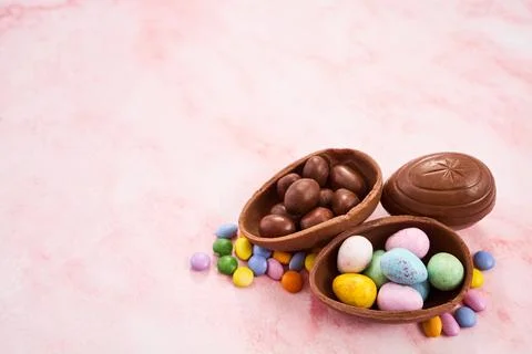 Easter chocolate egg candy spilling on pink background Stock Photos