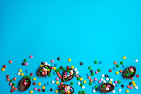 Easter chocolate egg with colorful explosion of candies and sweets on a blu.. Stock Photos