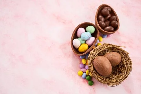 Easter chocolate eggs and candy in nest on pink background Foto stock