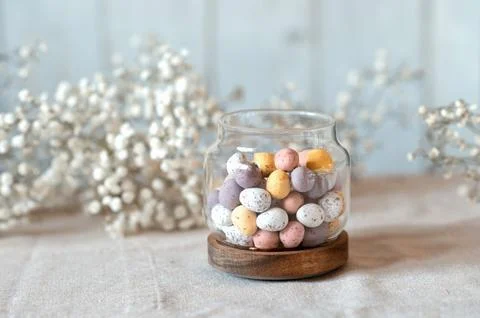 Easter chocolate Multi-Colored eggs in pastel colors in glass jar with Stock Photos