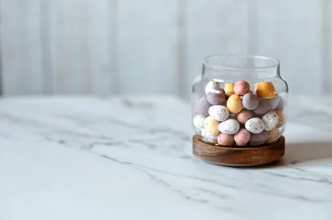 Easter chocolate Multi-Colored eggs in pastel colors in glass jar with copy Stock Photos
