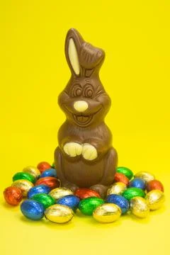 Easter. Chocolate rabbit on a yellow background and chocolate eggs. vertically Stock Photos