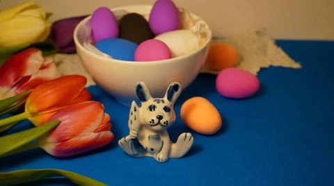 Easter with colored chicken eggs in a white plate with a porcelain rabbit figuri Fotos de archivo