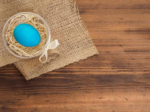 Easter colored egg on burlap and old wooden texture table. Mock up for your Fotos de archivo